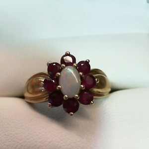 . .14K YELLOW GOLD RING WITH OVAL OPAL CENTER HALOED BY ROUND RUBIES