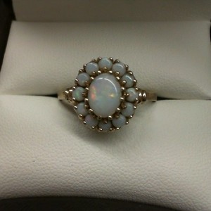  10K YELLOW GOLD WITH 1 OVAL CENTER OPAL SURROUNDED BY 12 SMALL ROUND OPALS